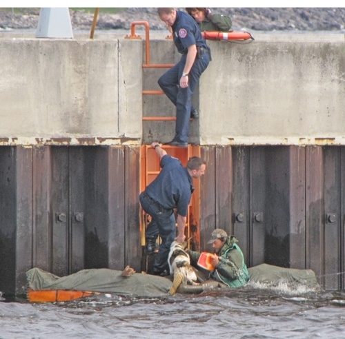 Erik Simula of Hovland bails water from his canoe while a Duluth firefighter holds his dog